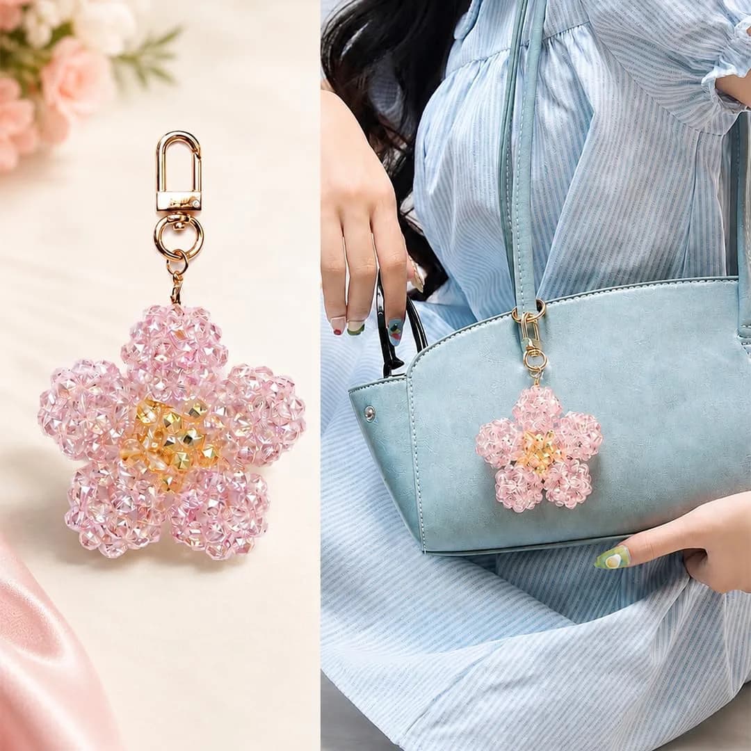 A pink flower of faceted glass beads with a yellow center, on a gold-tone clasp, and the same keychain on a blue handbag