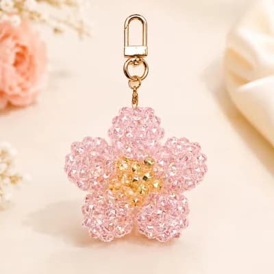 The pink flower keychain on a cream cloth, its beads catching the light