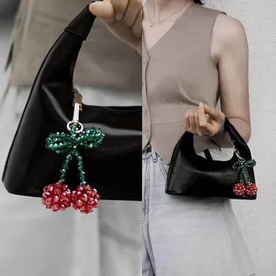 The cherry keychain hanging from a black handbag