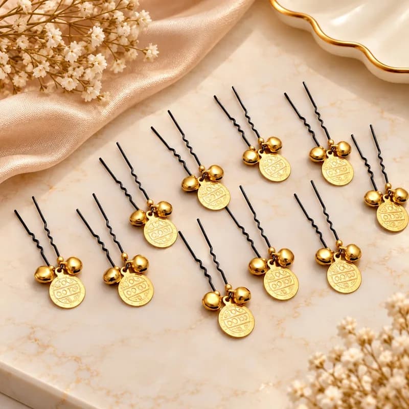 Twelve black U-shaped hair pins, each with a gold coin and two small gold bells, on marble
