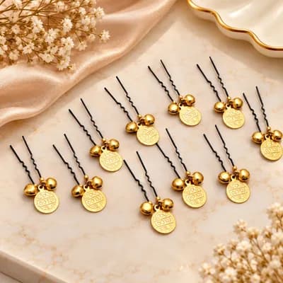 Twelve black U-shaped hair pins, each with a gold coin and two small gold bells, on marble