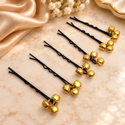 A close view of black bobby pins with clusters of gold bells