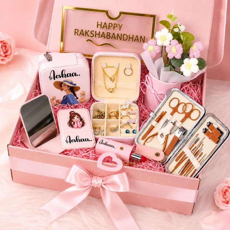 An open pink gift box holding a jewelry box, a mirror, a lipstick keychain and a manicure kit, each printed with the name Aeshaa