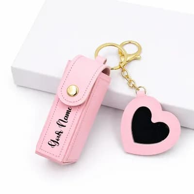 A pink lipstick case printed with “Your Name”, on a gold key ring with a pink heart mirror charm