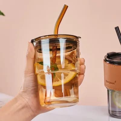A hand holding the tumbler, half full of a cold drink