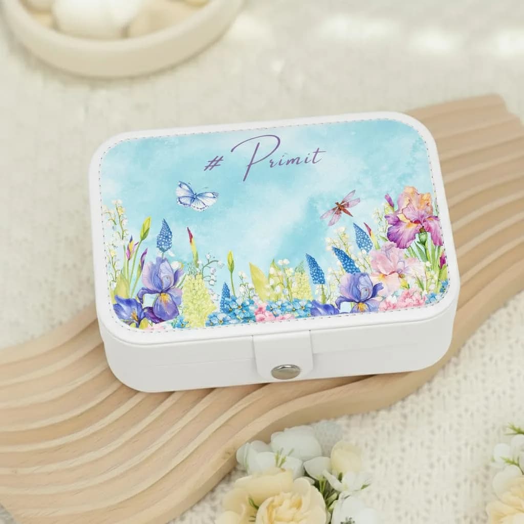 A white jewelry box printed with blue and purple irises and a butterfly, with “#Primit” in script