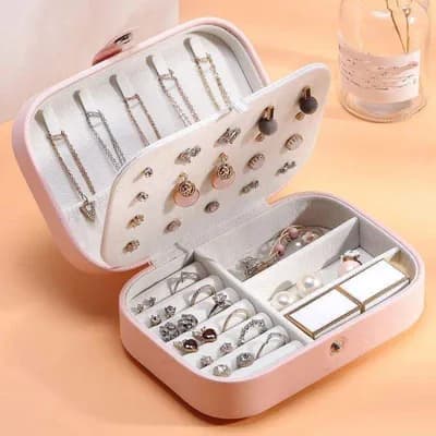 An open pink jewelry box full of necklaces, earrings and rings