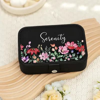 A black jewelry box printed with “Serenity” in white script above red, pink and purple wildflowers