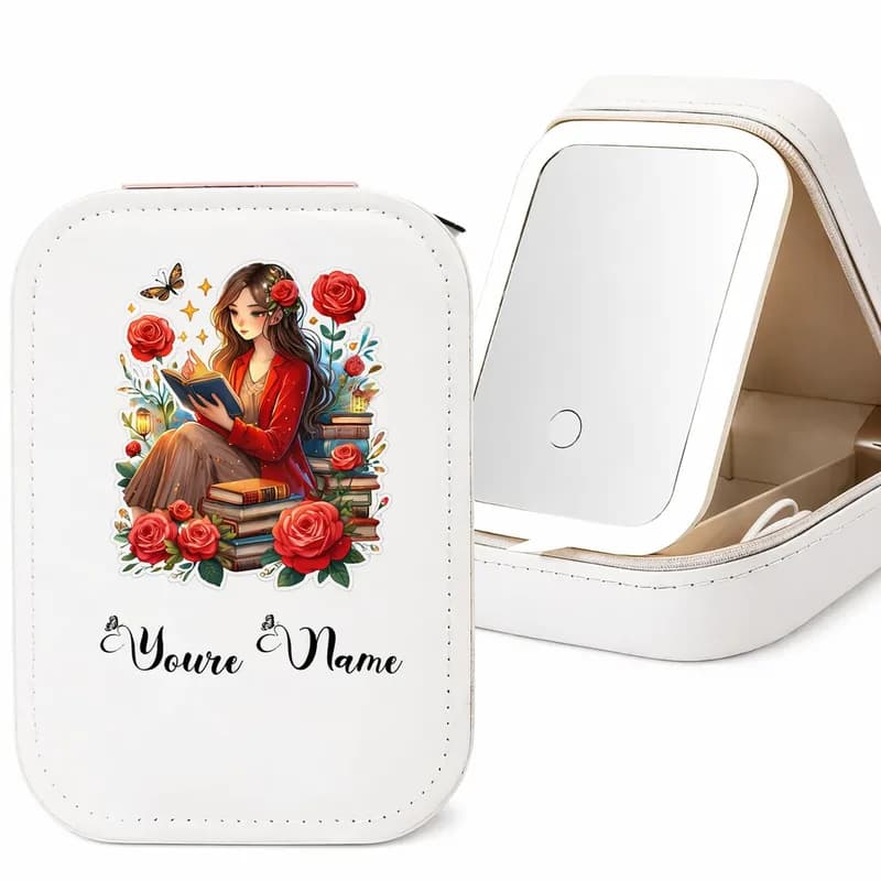 A white makeup case printed with a girl reading among books and red roses, with a sample name below, beside the open case and its mirror