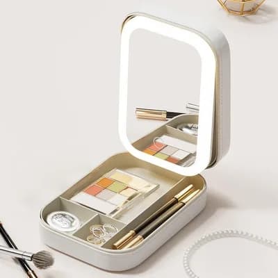 The open case: the lit mirror in the lid, and a palette, a compact, rings and pencils in the compartments below