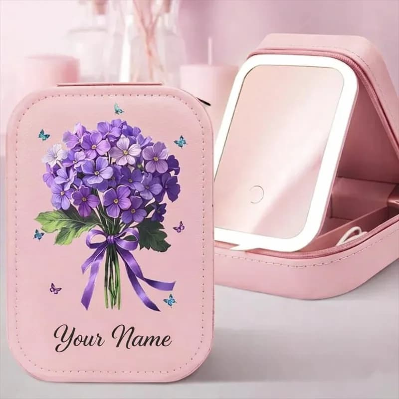 A pink makeup case printed with a bouquet of purple flowers tied with a ribbon, with “Your Name” below, beside the open case