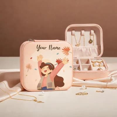 A peach mini jewelry box printed with a laughing girl throwing up her arms among autumn leaves, with “Your Name” above her, beside an open box