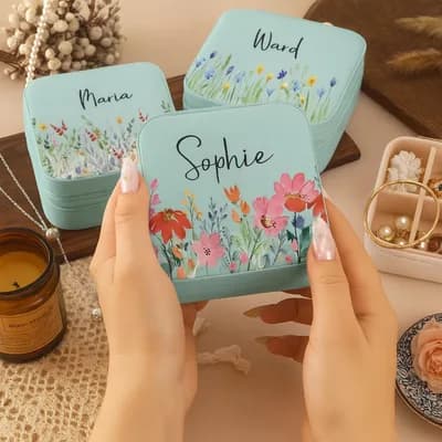 Mint mini jewelry boxes printed with flowers and the names Sophie, Maria and Ward, held in two hands