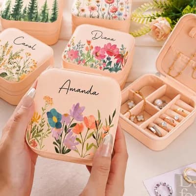 A peach box printed with flowers and the name Amanda, held in a hand above other named boxes