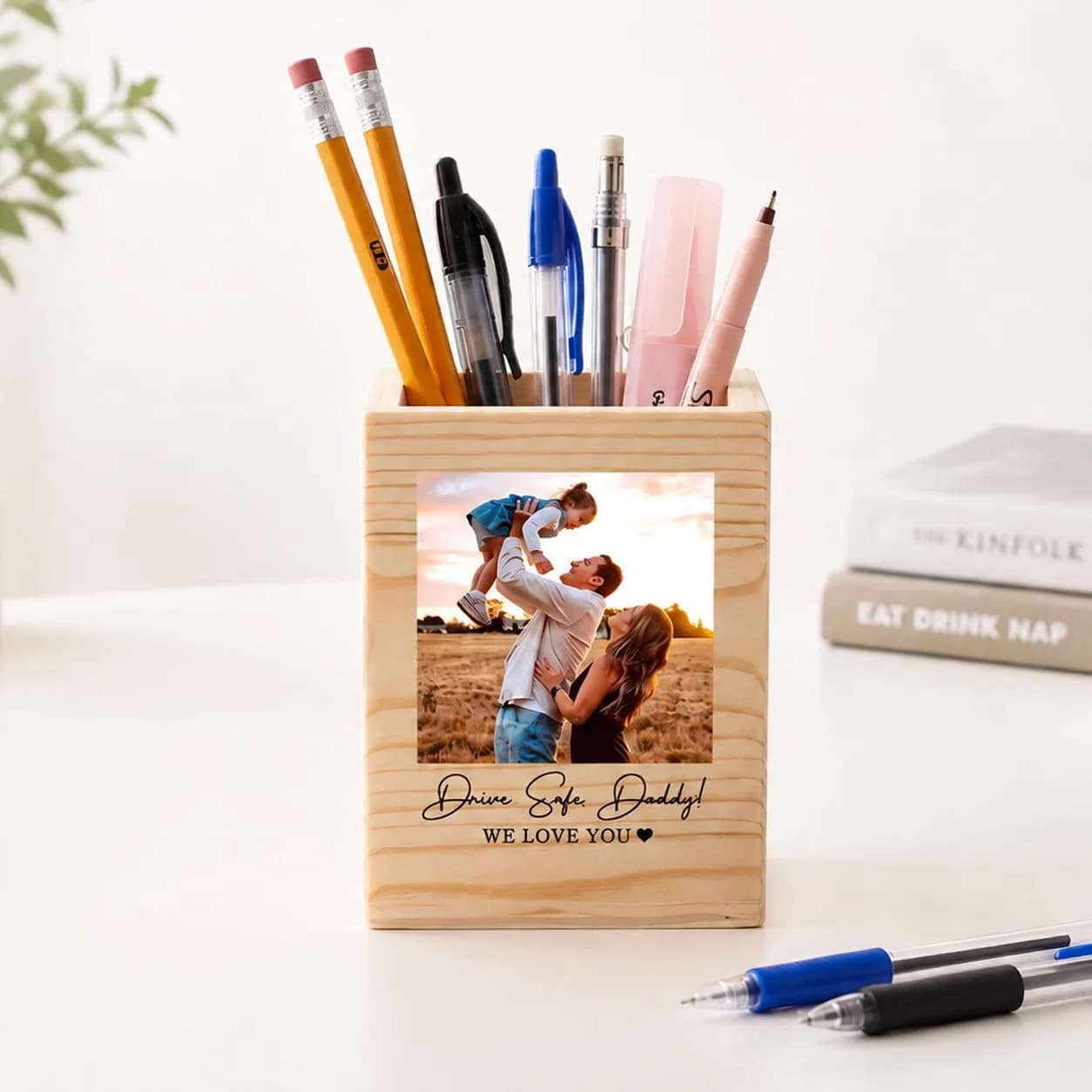A wooden pen holder printed with a photo of a father lifting his child and “Dear Super Daddy! We love you”, full of pens