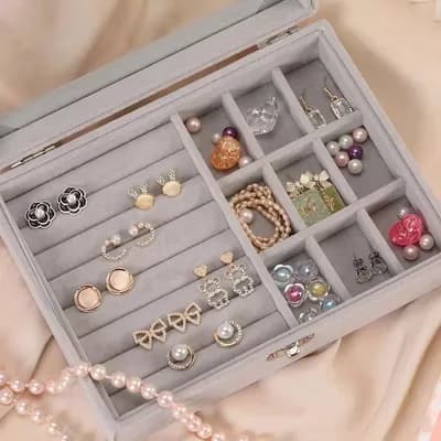 Inside the gray box: padded rows holding earrings, and a grid of small compartments with pearls, pendants and a bracelet