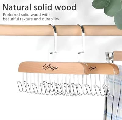 Two hangers on a rail, one engraved with the name Priya, under the words “Natural solid wood”